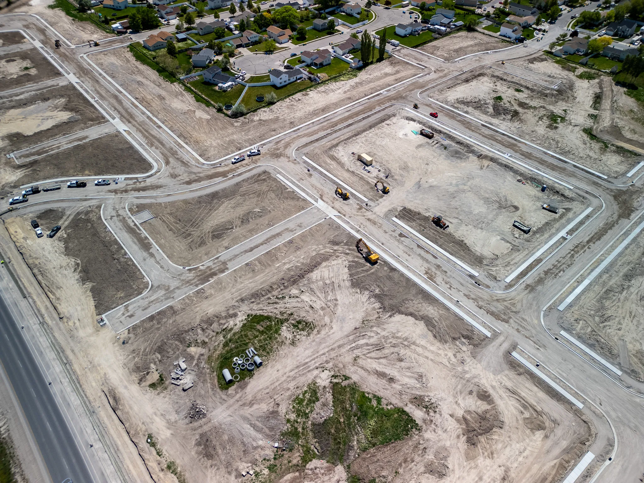 Aerial drone photograph of earth-moving equipment grading lots in a new Utah housing subdivision