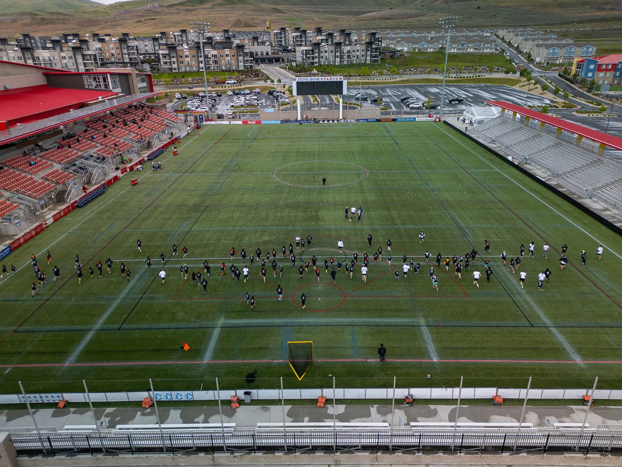 Aerial drone view of a Utah soccer stadium during a team practice with players spread across the pitch