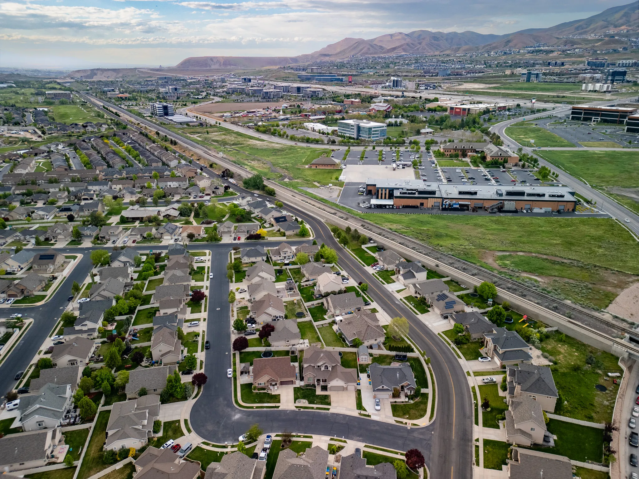 Wide aerial view of Utah County residential neighborhoods with the Wasatch front in the distance