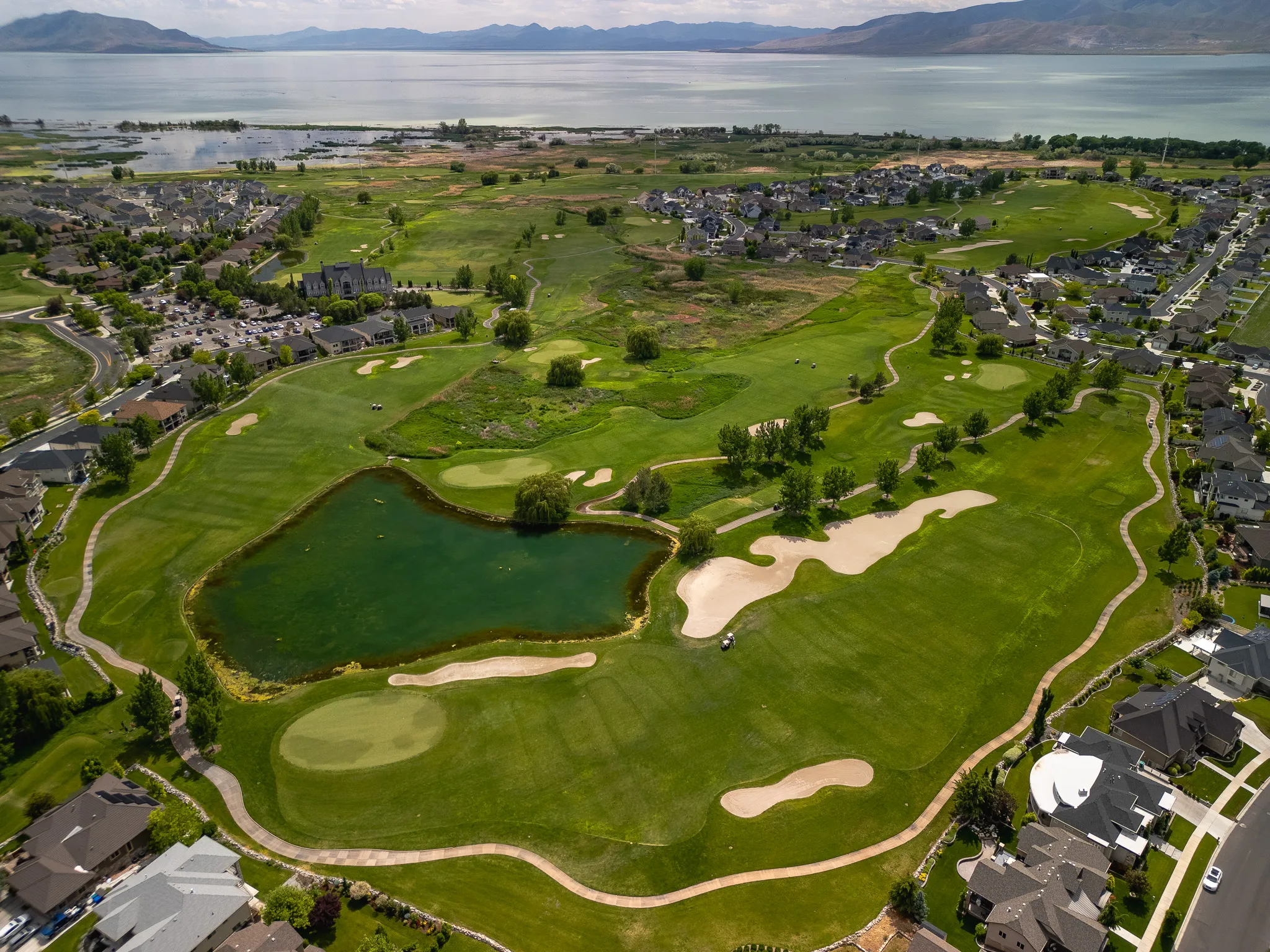 Aerial drone landscape of a manicured Utah golf course with Utah Lake and the Wasatch mountains beyond