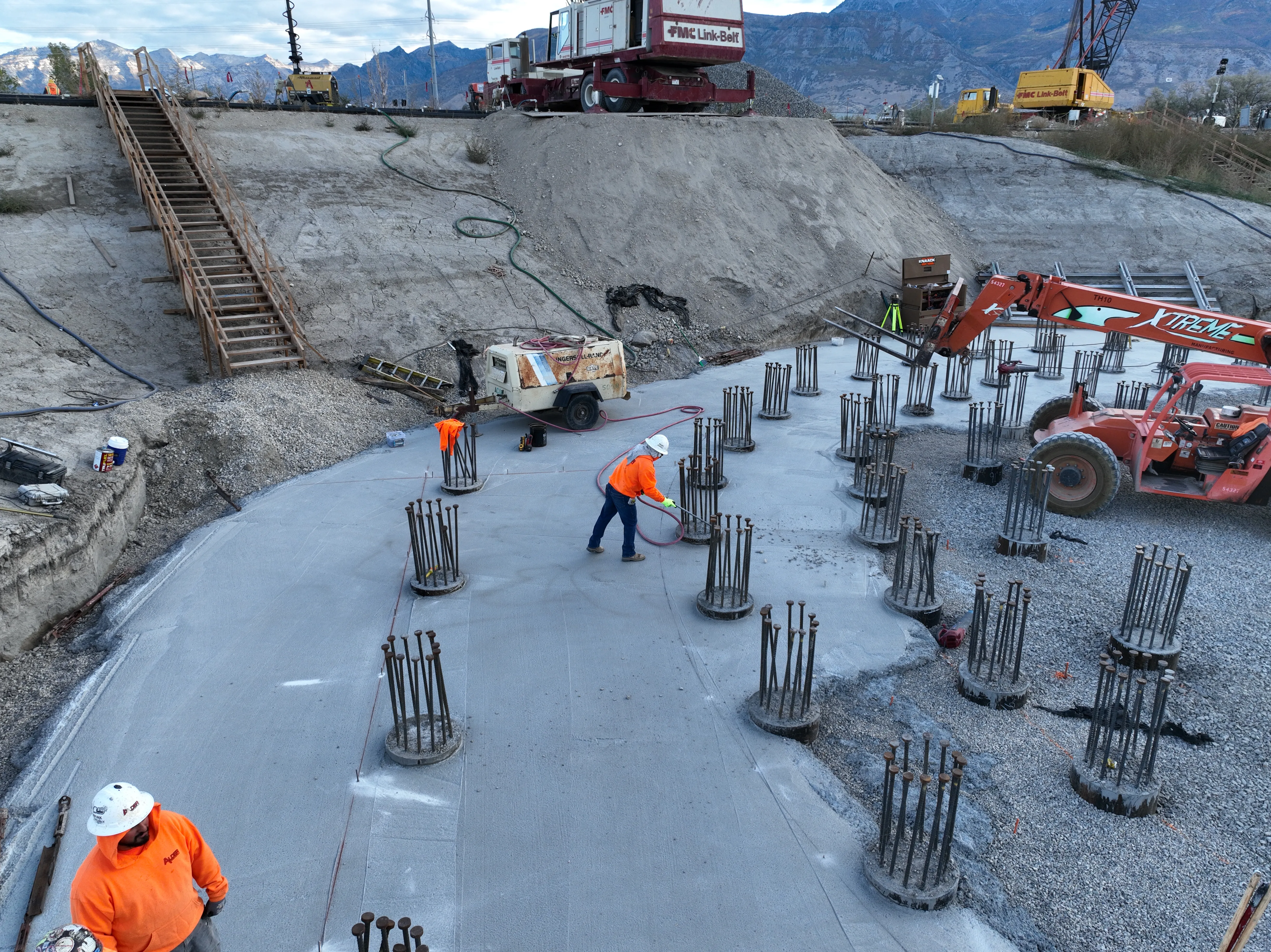 Drone view of construction crew placing rebar columns on a freshly poured concrete pad at the WR Meadows site, Salt Lake County, Utah